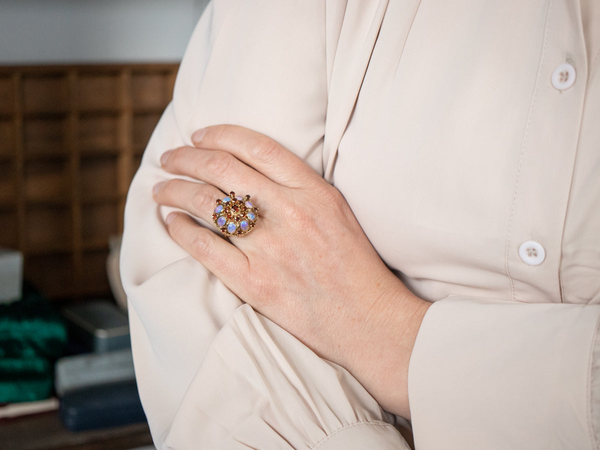 Anillo de cóctel con incrustaciones de ópalo y granate adornado