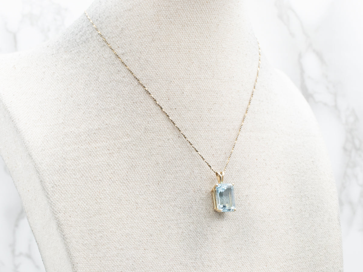 Sofisticado colgante con solitario de topacio azul y oro amarillo