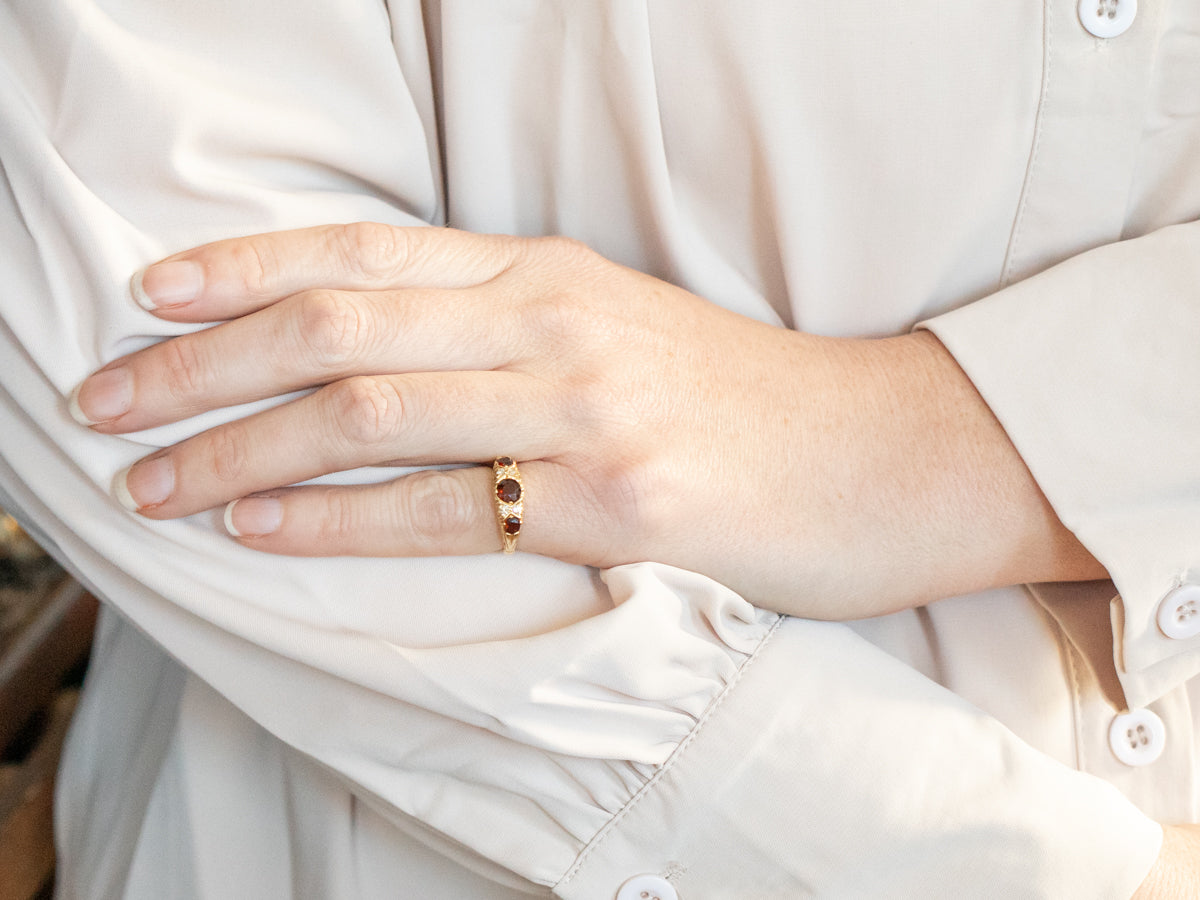 Anillo de oro amarillo con granate de talla redonda y detalles de diamantes