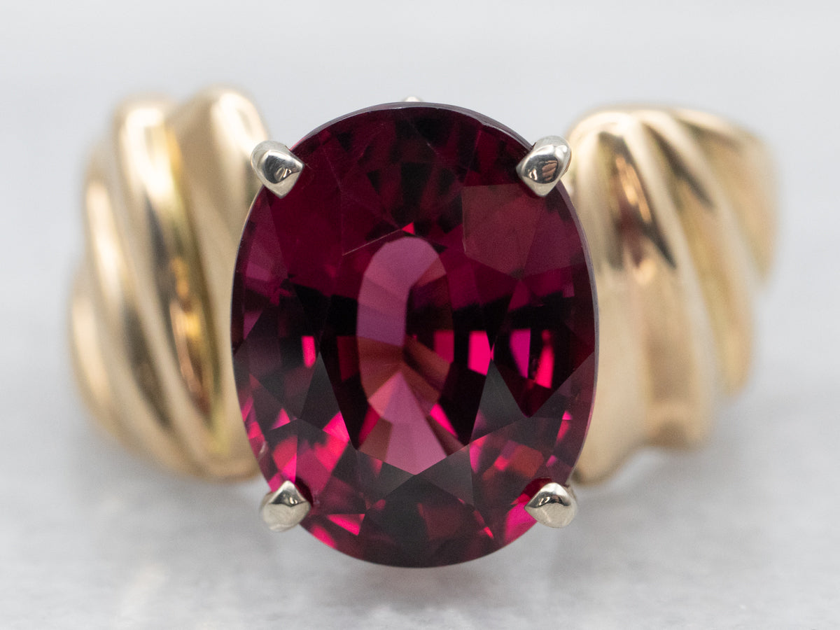 Anillo solitario de oro amarillo con granate rodolita de talla ovalada y hombros torcidos
