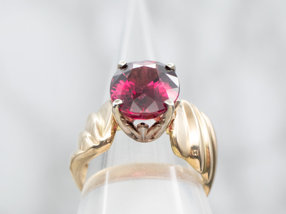 Anillo solitario de oro amarillo con granate rodolita de talla ovalada y hombros torcidos