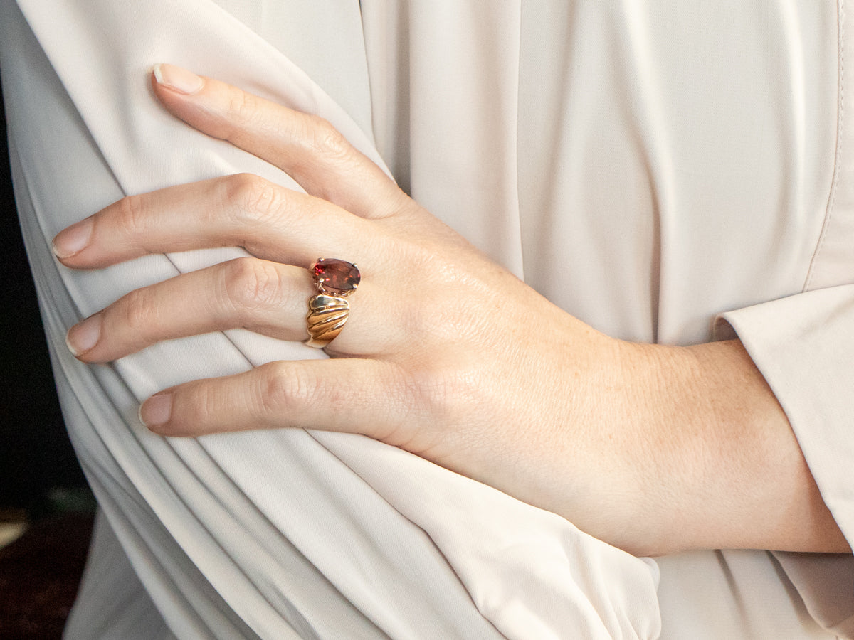 Anillo solitario de oro amarillo con granate rodolita de talla ovalada y hombros torcidos