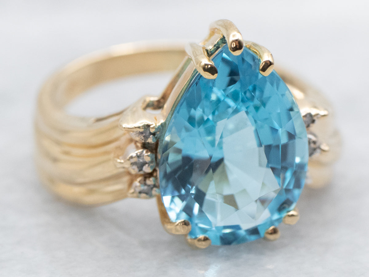 Anillo de oro amarillo con topacio azul de talla pera y detalles de diamantes