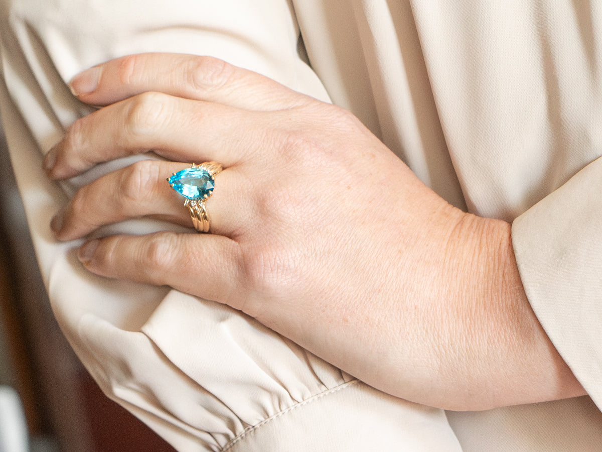 Anillo de oro amarillo con topacio azul de talla pera y detalles de diamantes