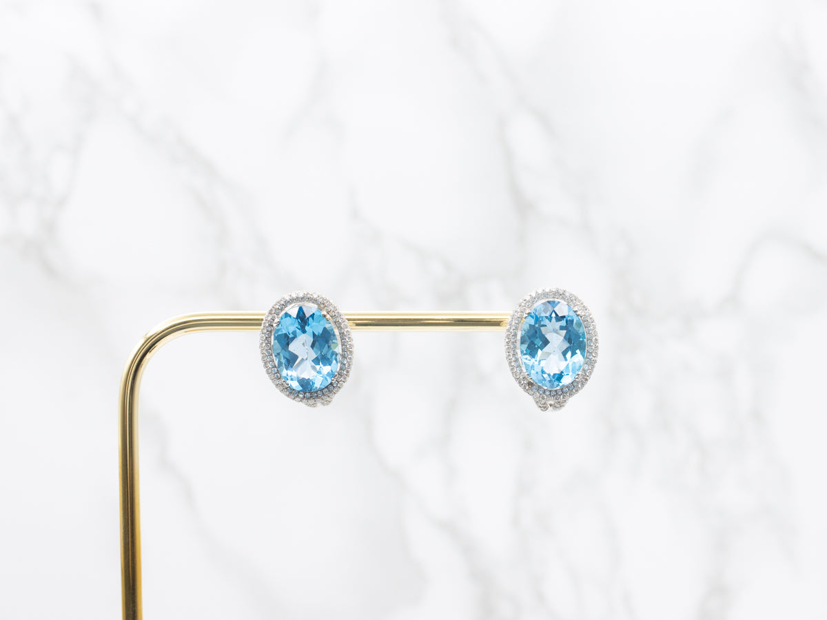 Aretes con halo de diamantes y topacio azul en oro blanco con respaldo Omega
