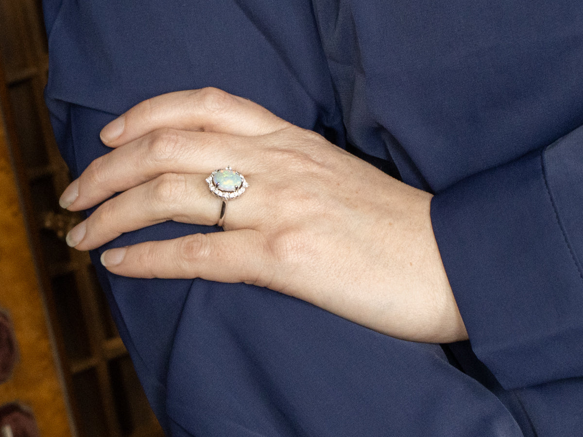 Anillo de cóctel con halo de diamantes y ópalo ovalado en oro blanco de 14 quilates